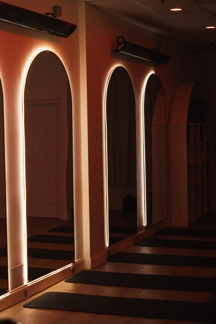 Mats laid out between glowing arched mirrors and infrared panels in the COREFLOW studio